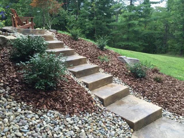 decorative concrete steps going up a hill, with mulch and shrubs on both sides of it