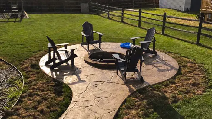 Small brownish Circle Stamped Concrete patio With a Built In raised Firepit ring