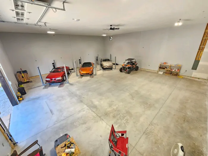 Large indoor concrte parking lot with cars and motorcycles.